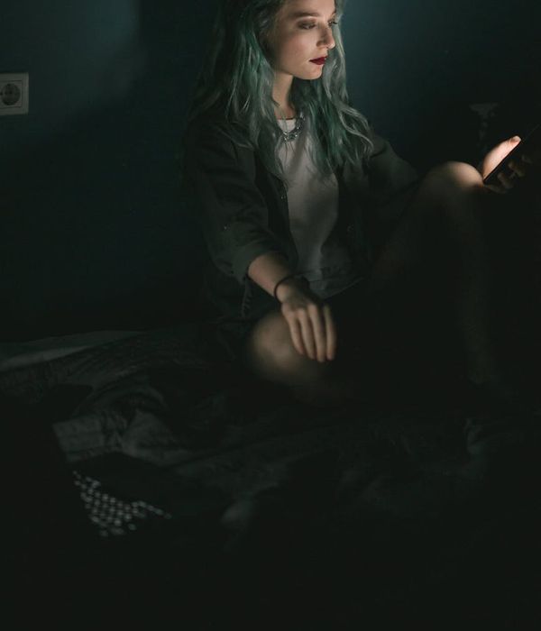 Woman with a calm and focused expression in a dimly lit room.